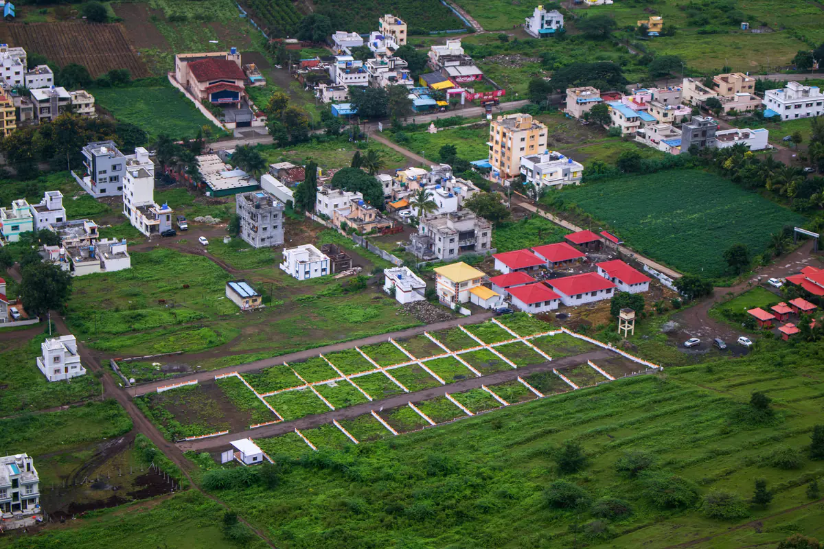 Aerial view of a residential layout with marked plots, new houses and green fields